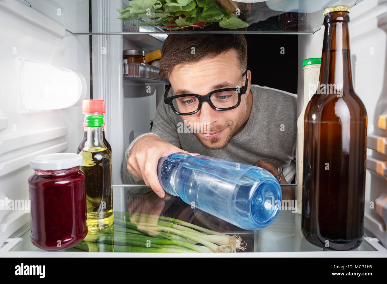Man grabbing a water bottle in the fridge Stock Photo