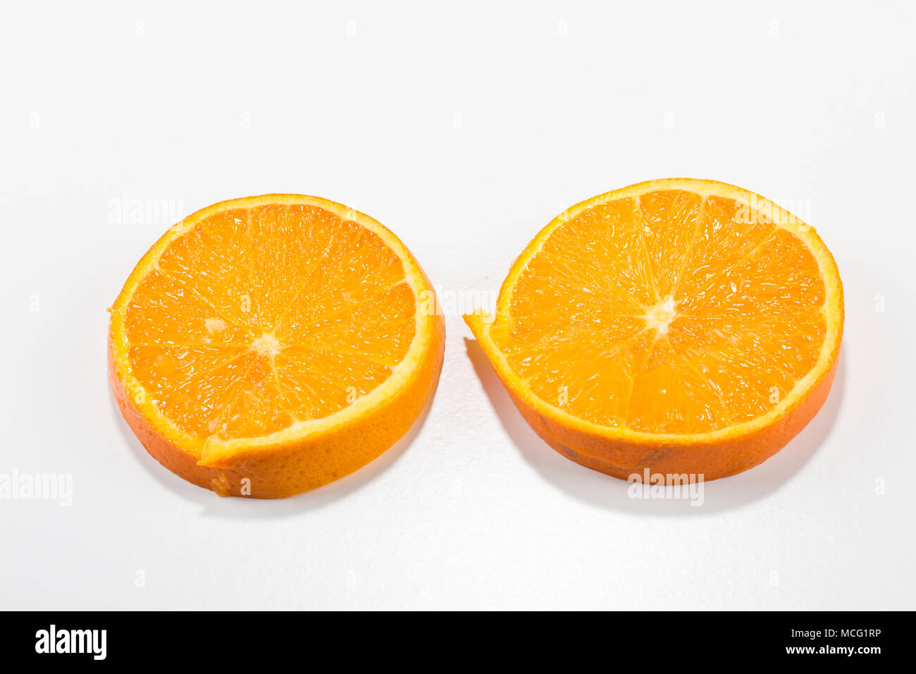 two fresh juicy round orange slices with thick peel and lots of fruit ...
