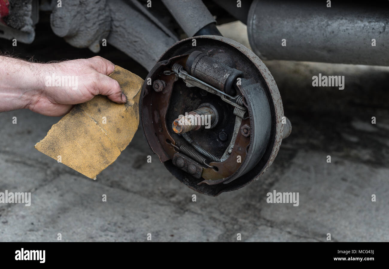 The man repairing brake drums for car and cleans brake pads with