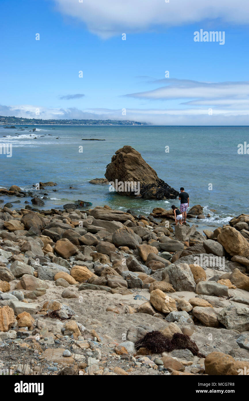 Father and daughter exploring tide pools on beach in Malibu, California Stock Photo