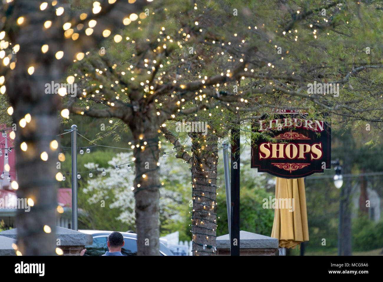 Outdoor dining and walkway under lighted trees along the shops and tree-lined Main Street in Lilburn, Georgia. Stock Photo