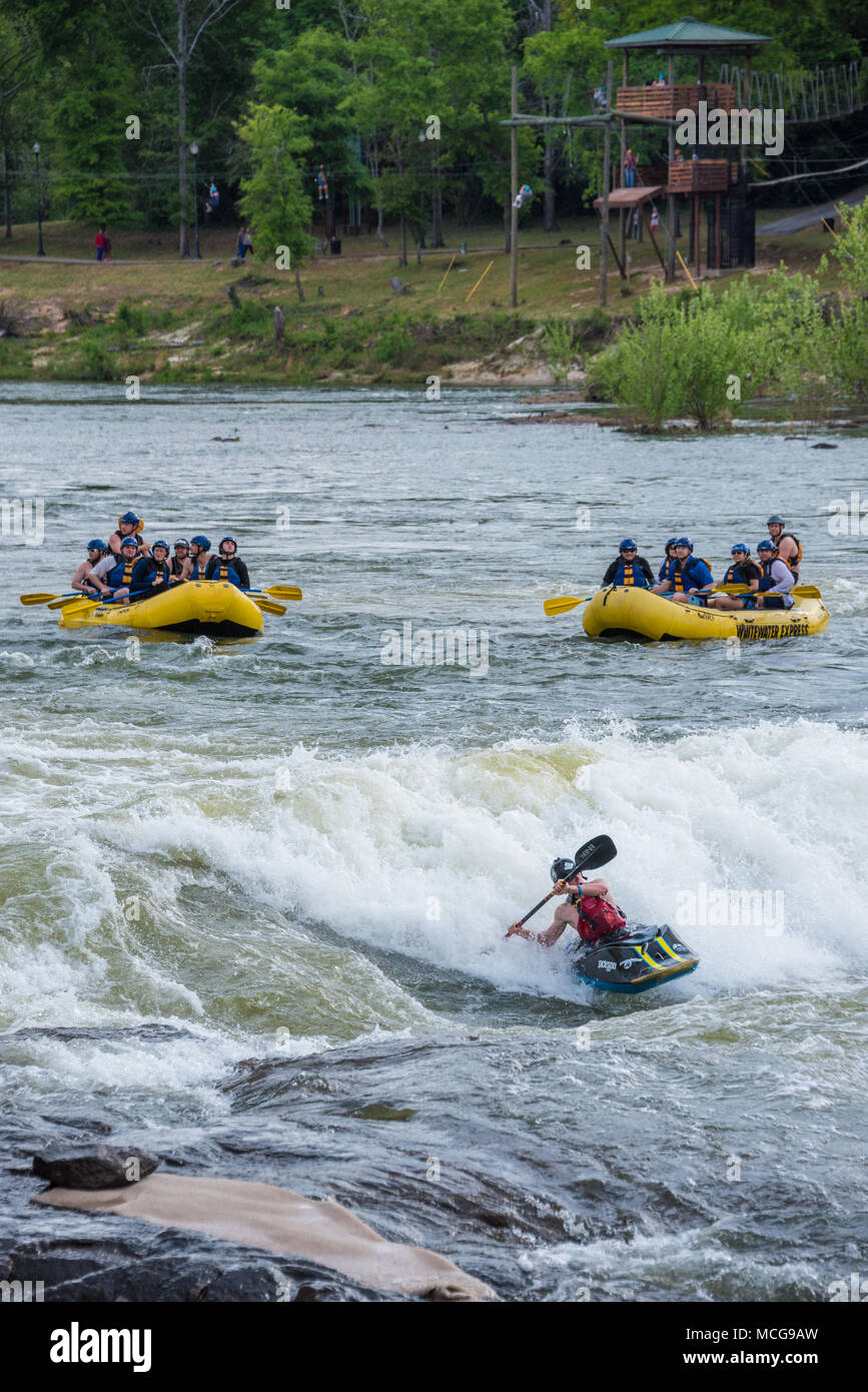 Whitewater rafters and a kayaker enjoy the rapids at Paddle South while zipliners cross the Chattahoochee River from Columbus, GA to Phenix City, AL. Stock Photo