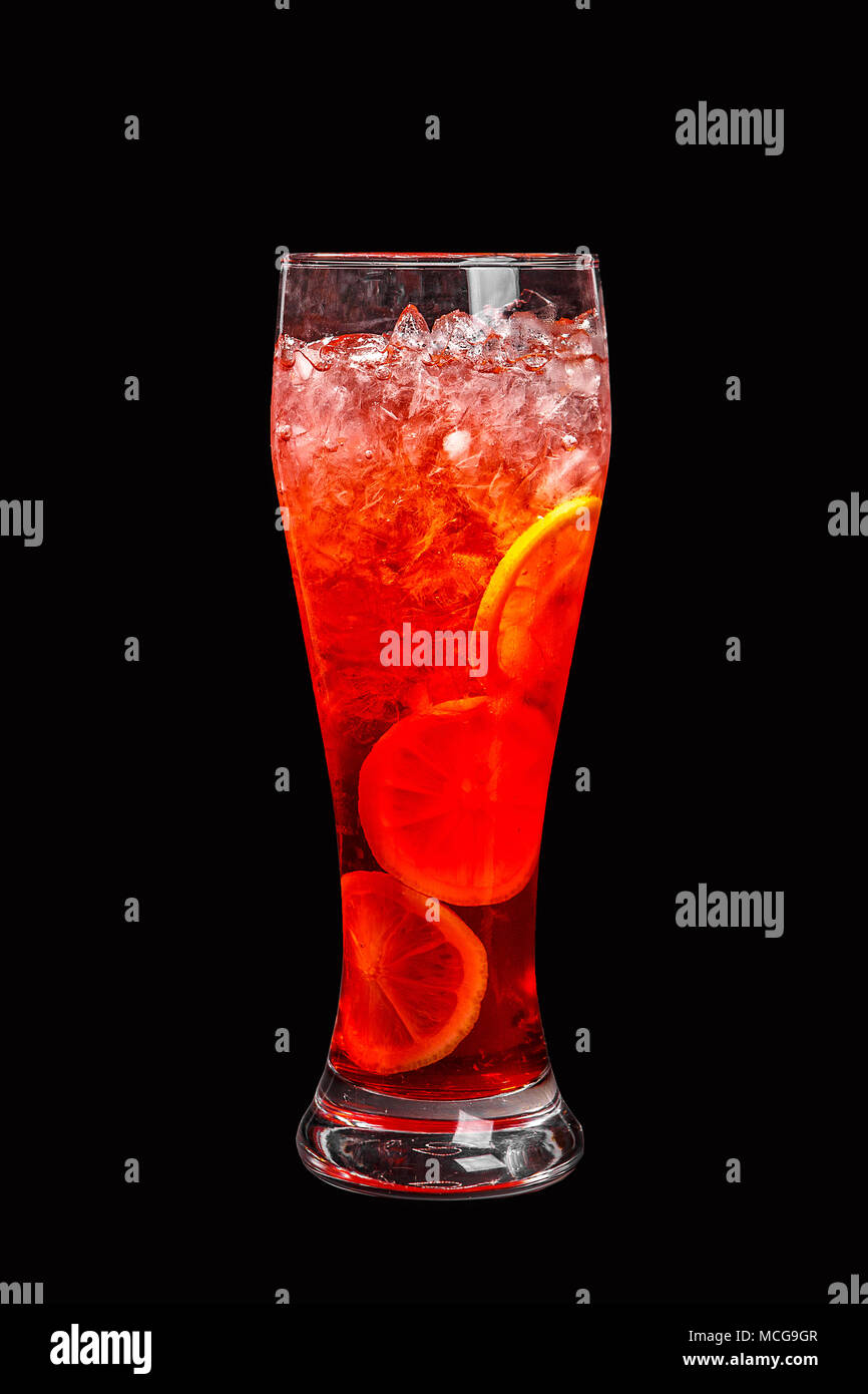 Single-color transparent cocktail, orange, red refreshing in a tall glass with crushed ice frappe and round slices of orange, lemon. Side view. Isolat Stock Photo