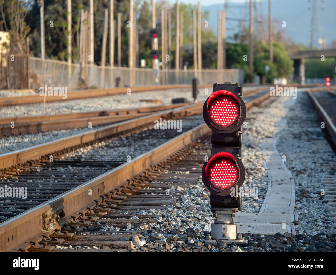 A railroad color position light sits on ground level flashing red stop