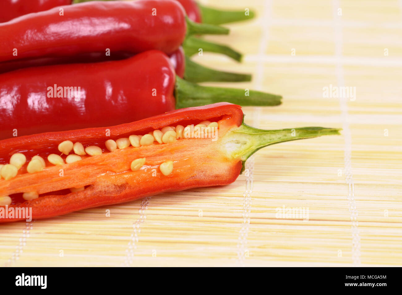 Red chili peppers cut half inside showing seeds on a bamboo asian mat