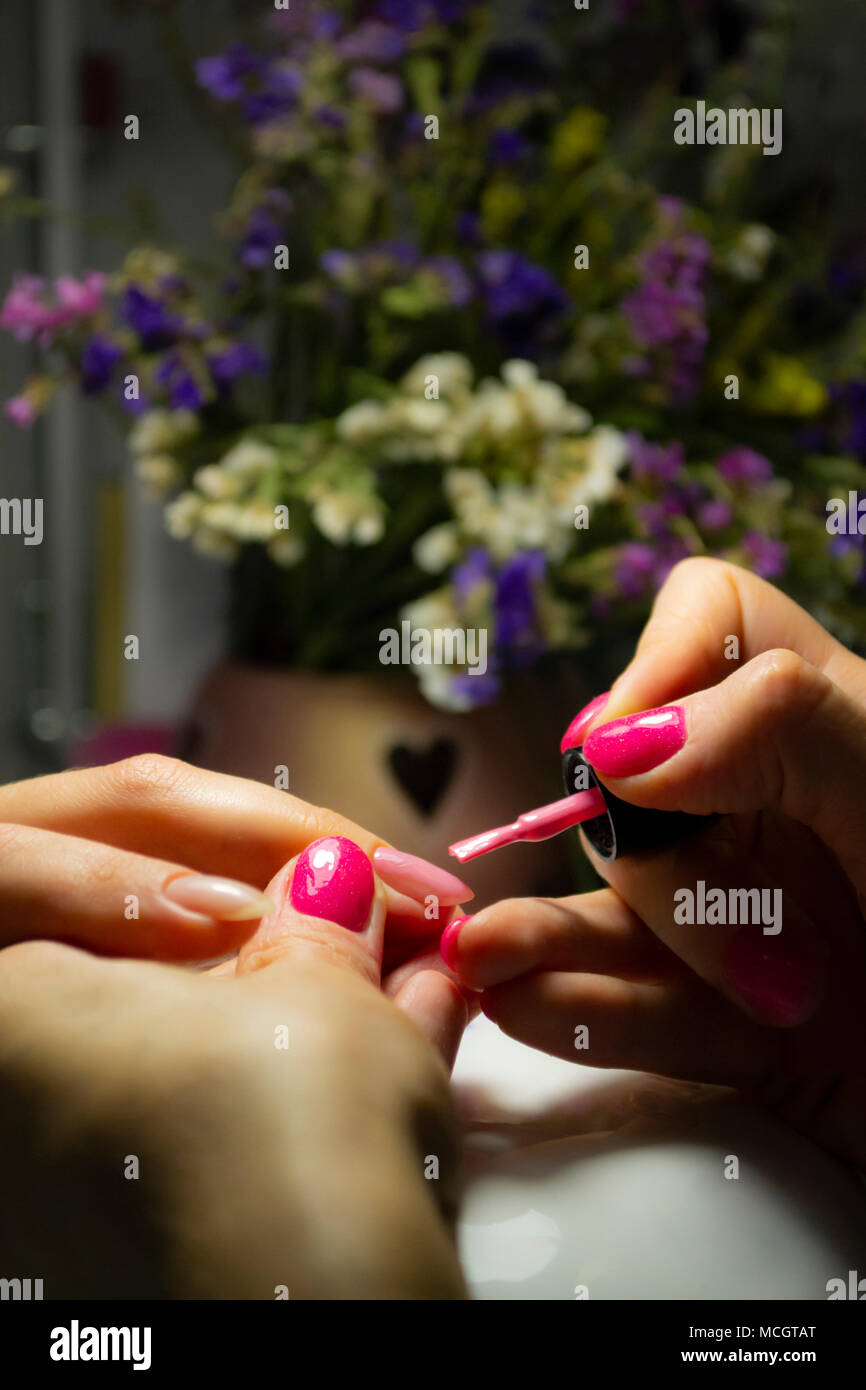 Manicure nail paint. Beautician applying nail polish to female nail in