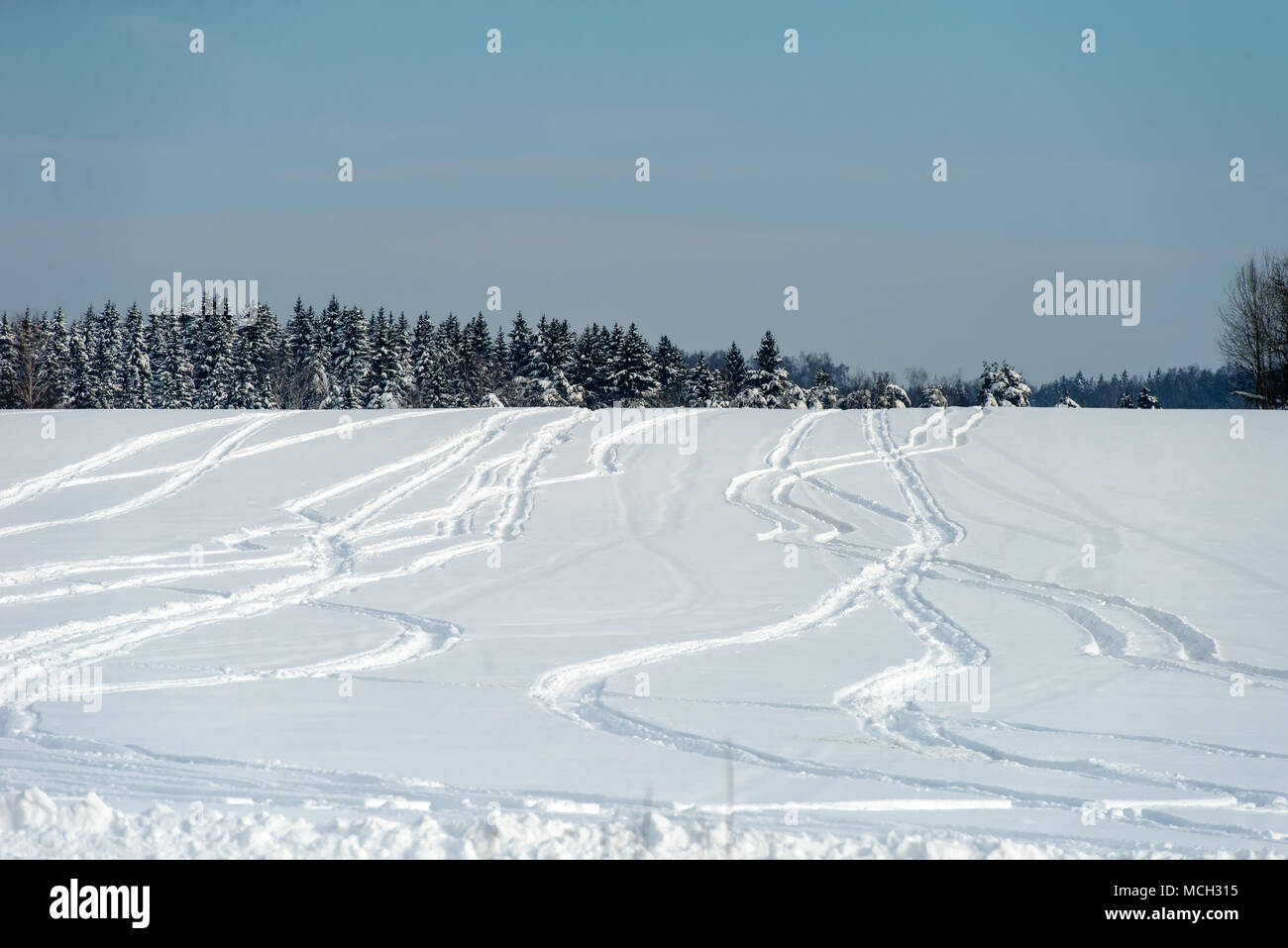 Drawings from snowmobile tracks on a snow-covered field in a winter day Stock Photo