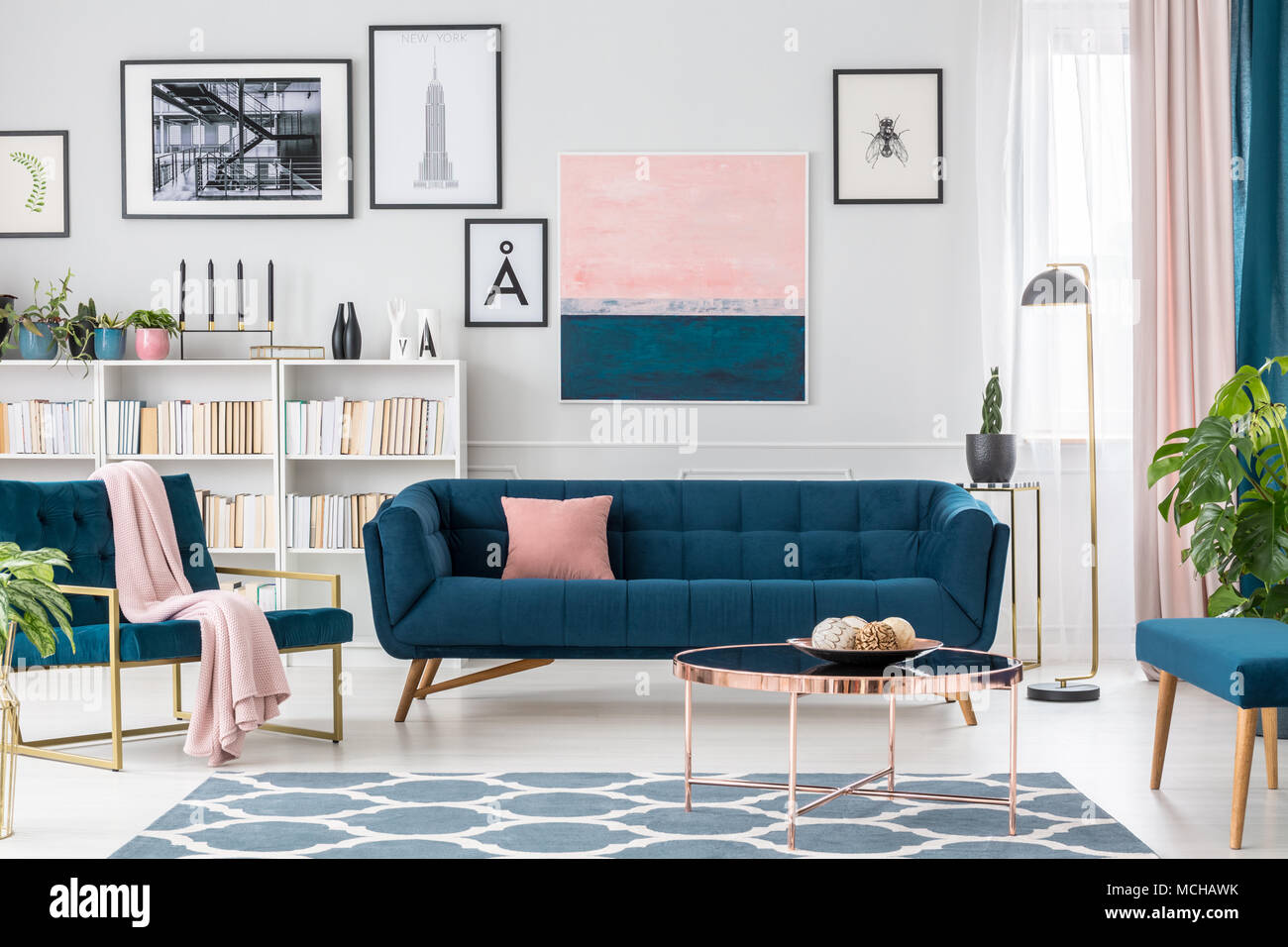 Modern living room interior with blue sofa, rug, art collection and pink  details Stock Photo - Alamy