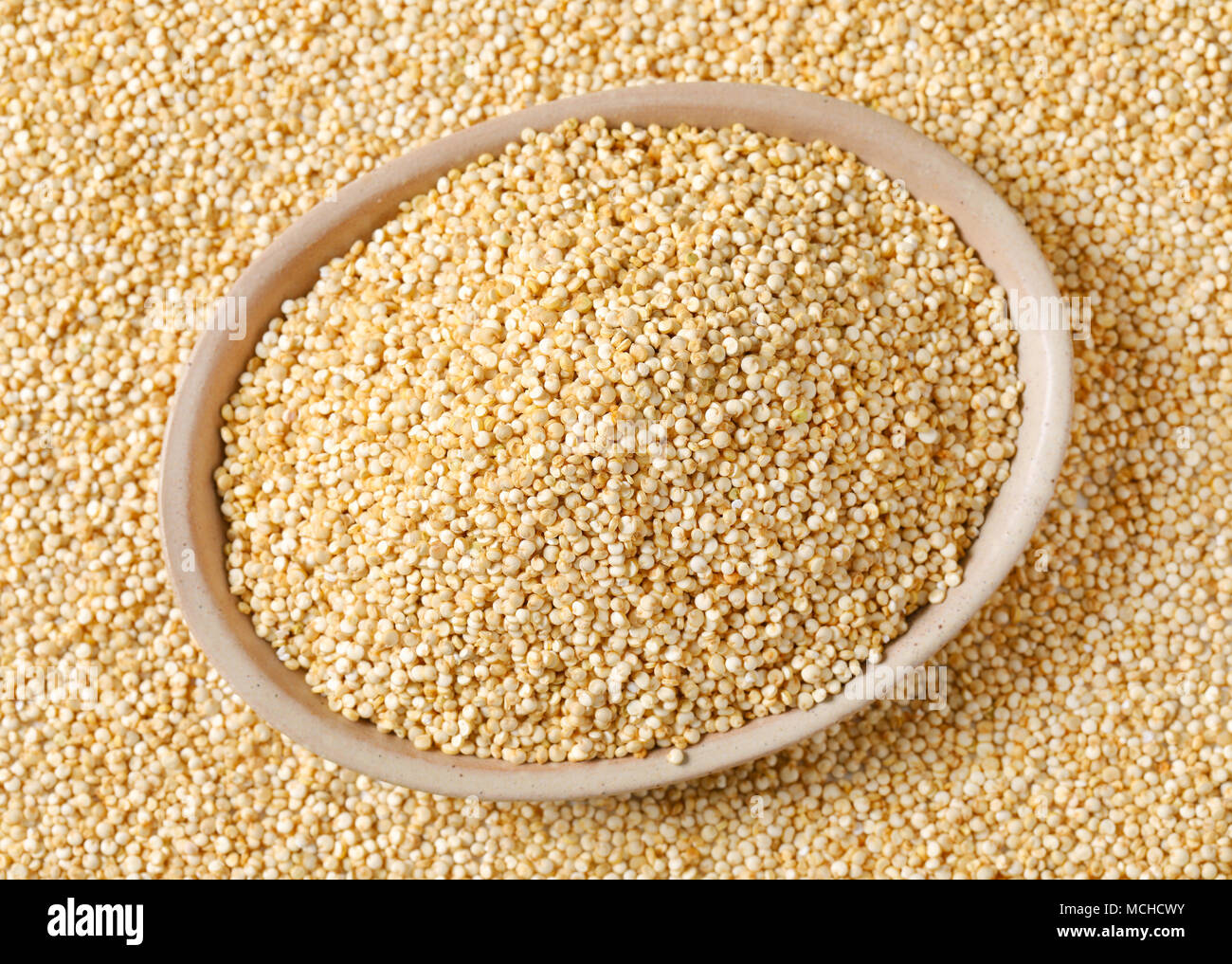 bowl of white quinoa seeds on quinoa background Stock Photo