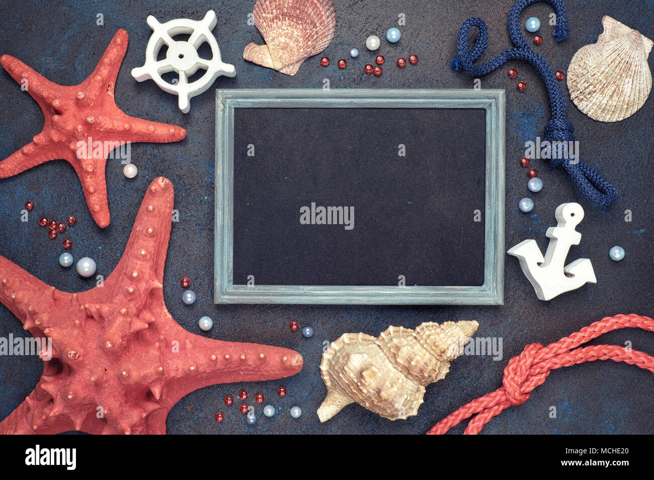 Blank blackboard with sea shells, rope and star fish on dark background, text space Stock Photo
