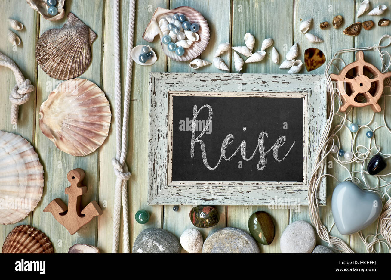 Blackboard With Maritime Decorations on light wood, text in German. 'Reise' means 'Vacations'. Stock Photo