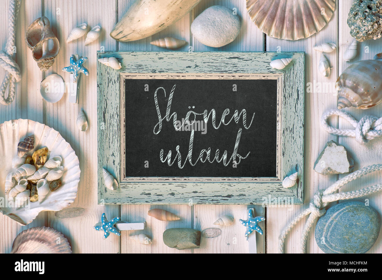 Blackboard With Maritime Decorations on light wood, text in German, 'Shonen urlaub' Means 'Happy holidays' Stock Photo