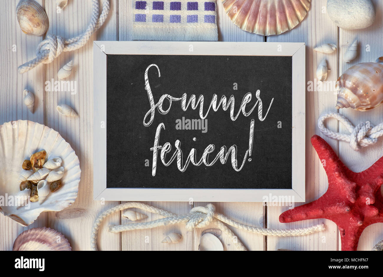 Blackboard With Maritime Decorations on light wood, text in German, 'Sommerferien' Means 'Summer Holidays' Stock Photo