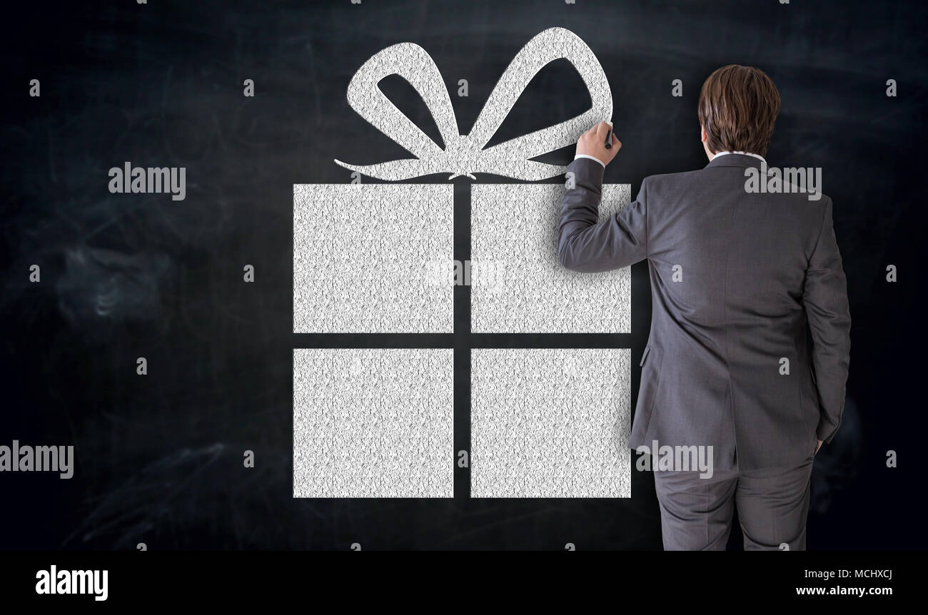 Businessman paints gift on blackboard concept. Stock Photo