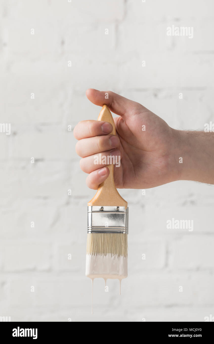 cropped image of man holding brush in white paint Stock Photo