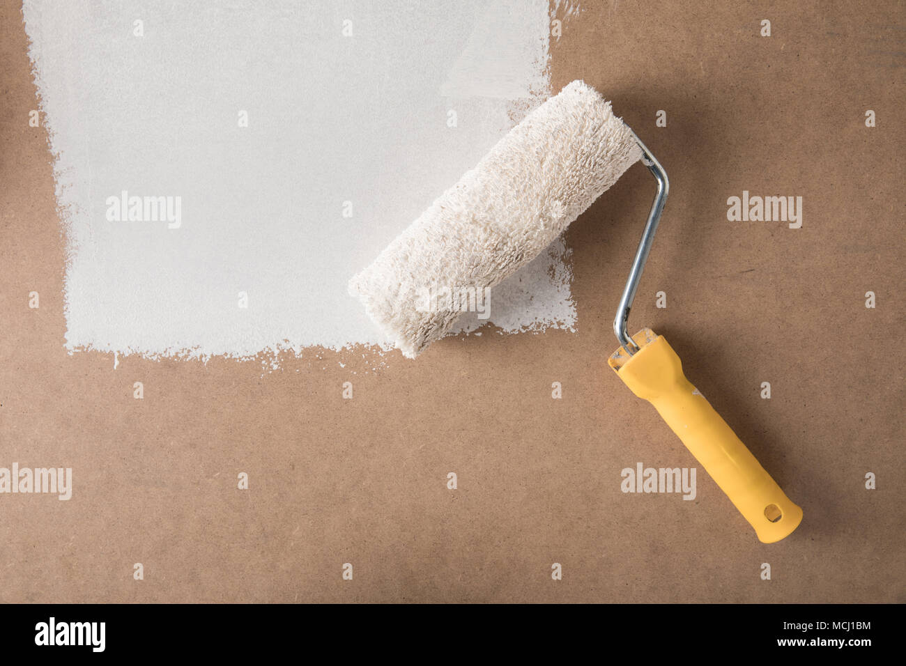 paint roll brush in white paint on plywood surface Stock Photo Alamy