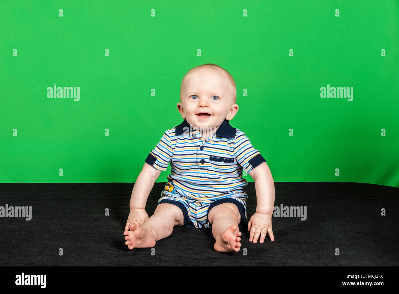 10-month-old-happy-baby-boy-on-a-green-background-playing-with-his