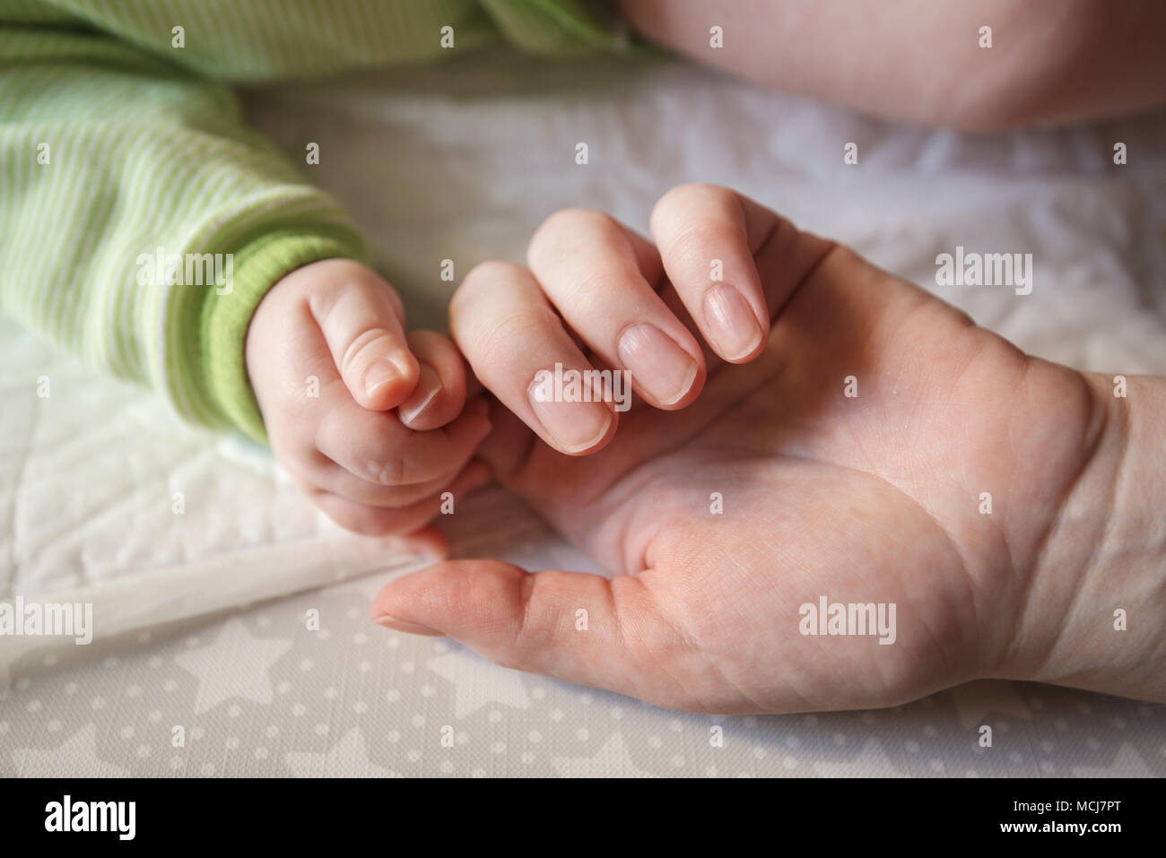 Mother touching baby's hand, close up with selective focus Stock Photo