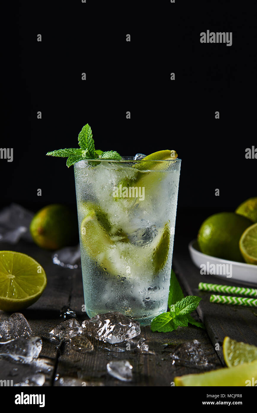 Mojito cocktail with lime and mint in highball glass with ice on a dark