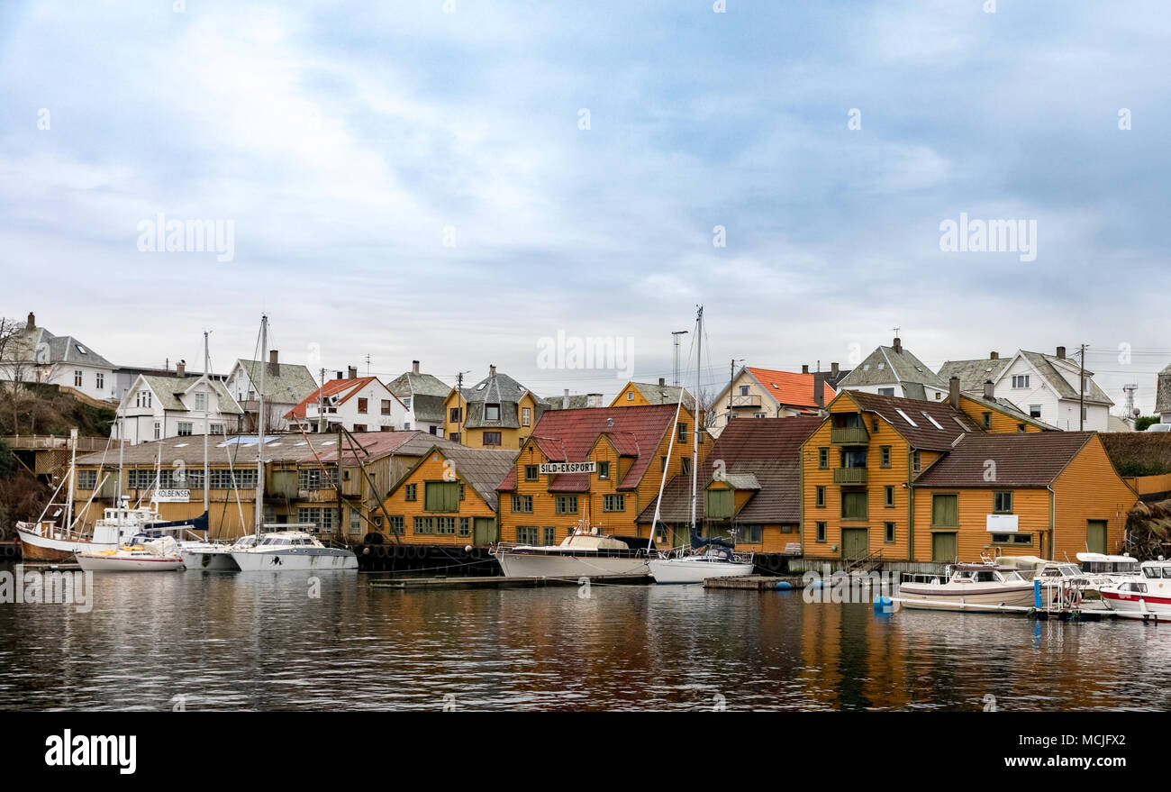 Haugesund, Norway - January 9, 2018: Old wooden houses on the island Risoy, boats and fishing industry buildings. Sild-eksport meaning Herring-export in norwegian. Stock Photo