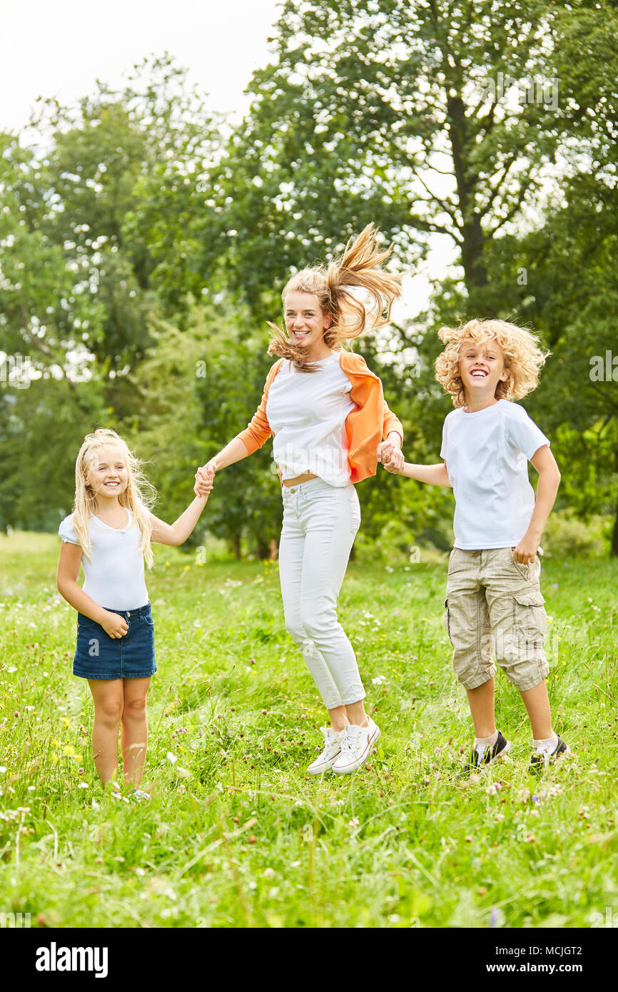 Mother plays and jumps with her children in the garden in summer Stock Photo