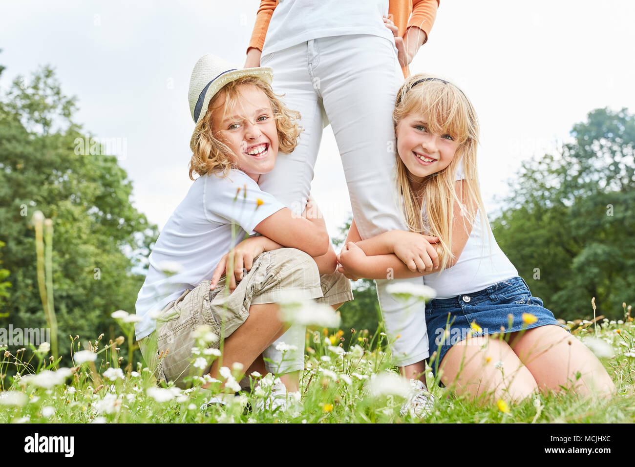 Brother and sister hug their mother in a meadow in summer Stock Photo ...