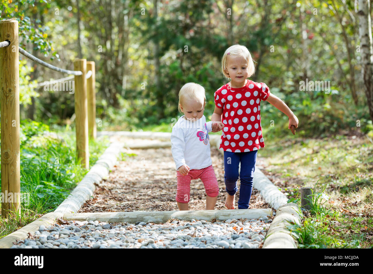 Infants, siblings walking together on a barefoot path, Germany Stock Photo