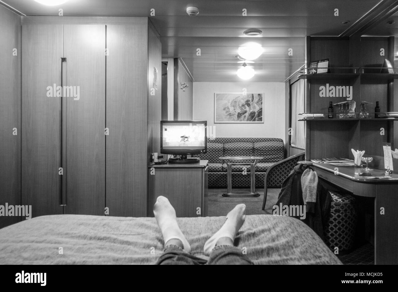 Man resting on bed and watching television, Athens, Greece Stock Photo