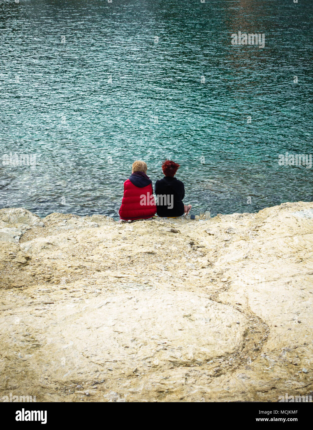 Rear view of two kids sitting at the coastline, Greece Stock Photo