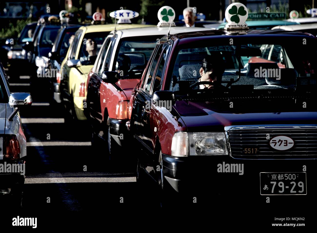 Walking out of the train station in Kyoto, Japan, many taxi cab drivers can be seen waiting for Fares seemingly in a state of boredom. Stock Photo