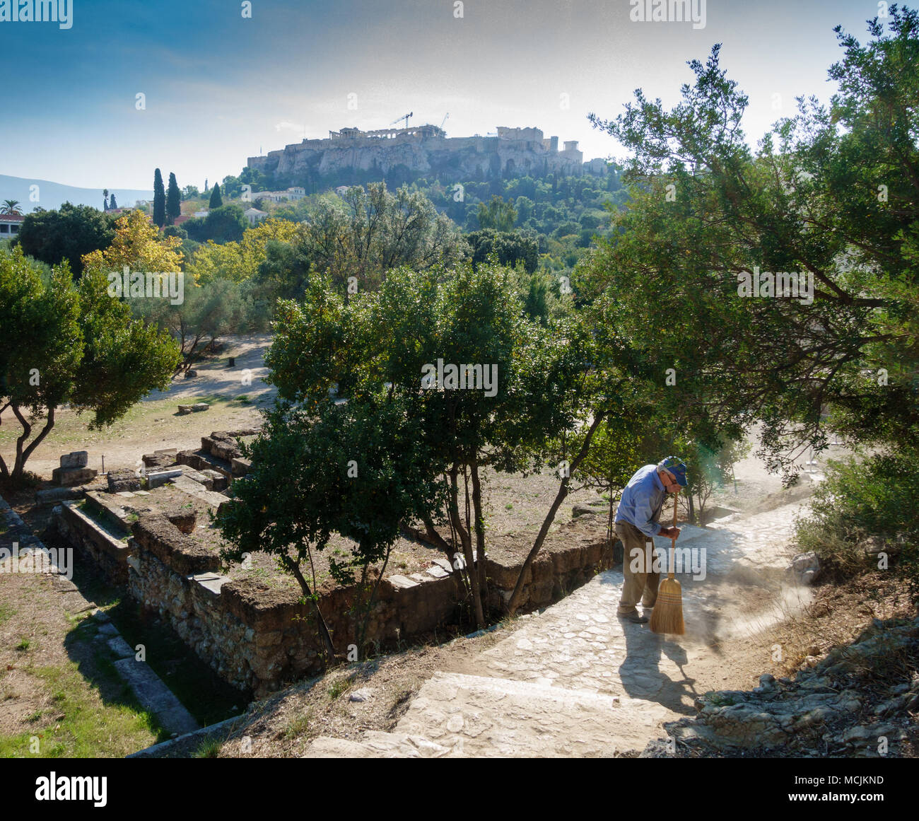 Old man sweeping with broom at garden, Athens, Greece Stock Photo