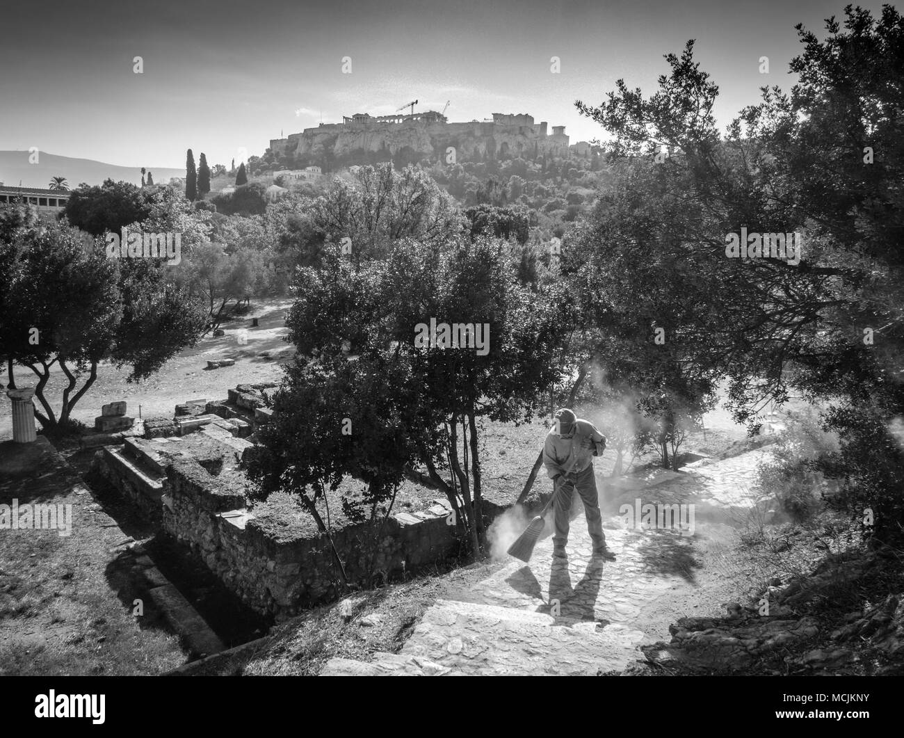 Old man sweeping with broom at garden, Athens, Greece Stock Photo