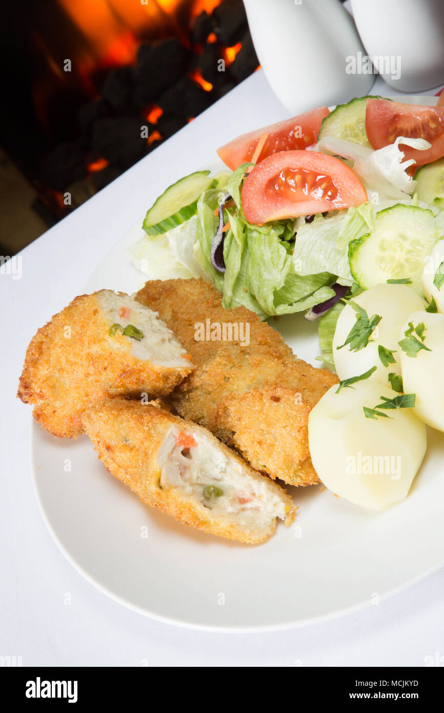 An English pub meal of deep fried breaded Chicken and vegetable rissoles with boiled potatoes and mixed salad Stock Photo