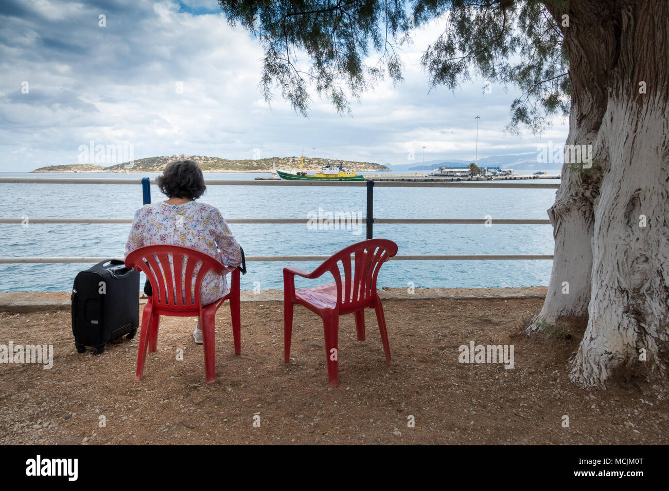 Rear view of senior woman sitting on chair admiring seascape Stock Photo