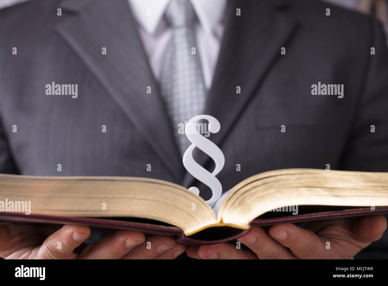 Close-up Of A Judge's Hand Holding Law Book With Paragraph Symbol Stock Photo