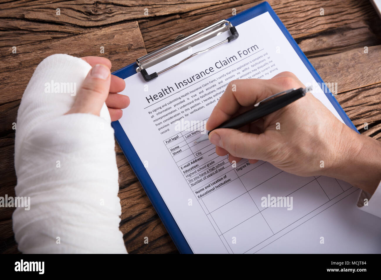 Closeup Of A Businessperson With Broken Arm Filling Health Insurance