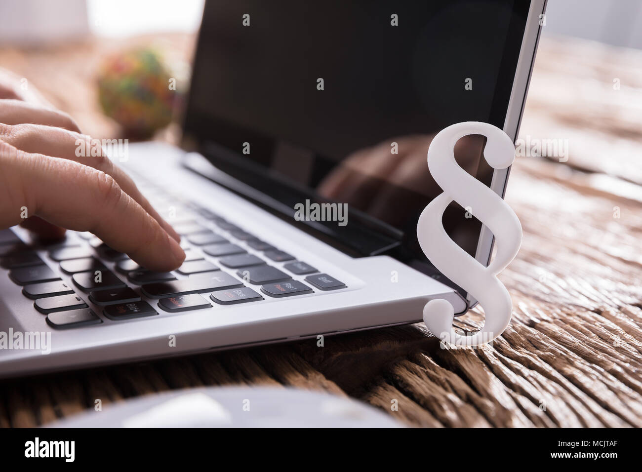 Businessperson's Hand Using Laptop With Paragraph Symbol On Wooden Desk Stock Photo