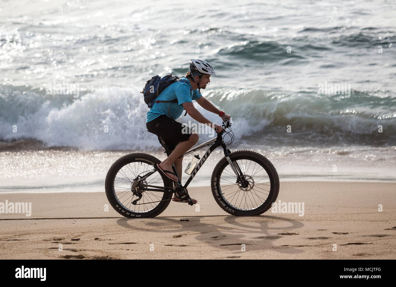 Durban, South Africa, April 9 - 2018: Man riding bicycle along the beach. Stock Photo