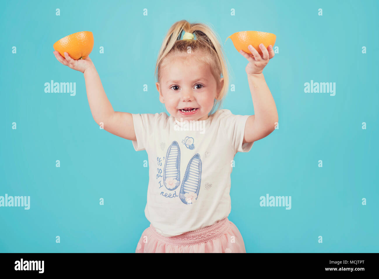 smiling baby with an orange on blue background Stock Photo