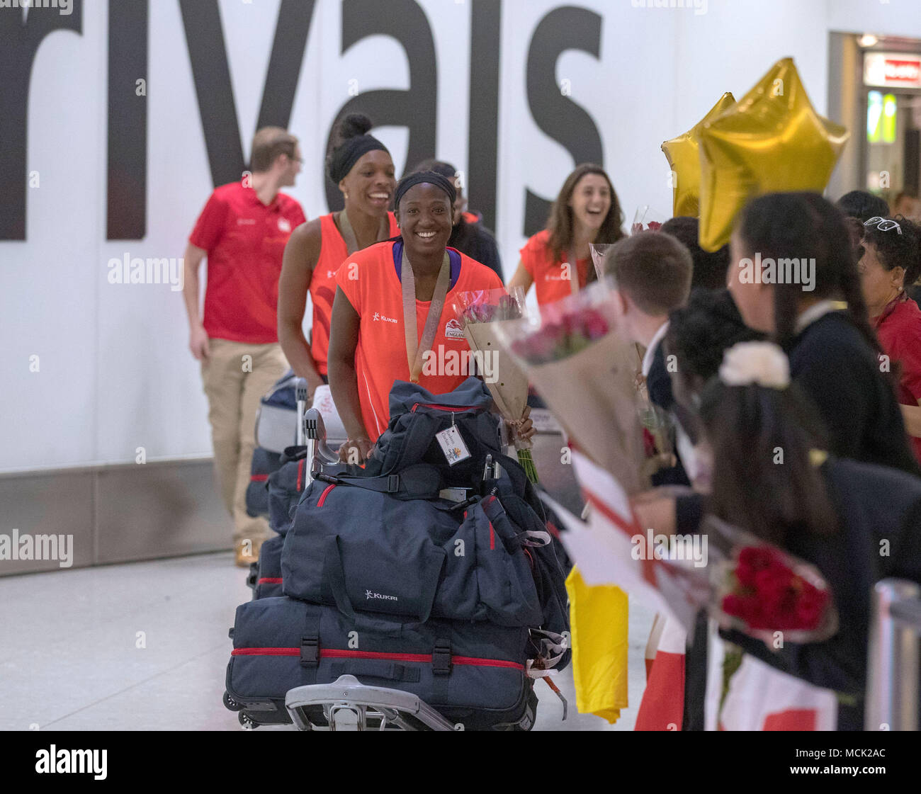 Members of the England women's Netball team which won a gold medal at the Commonwealth Games are greeted by local school children during a Homecoming at Heathrow Airport, London. Stock Photo