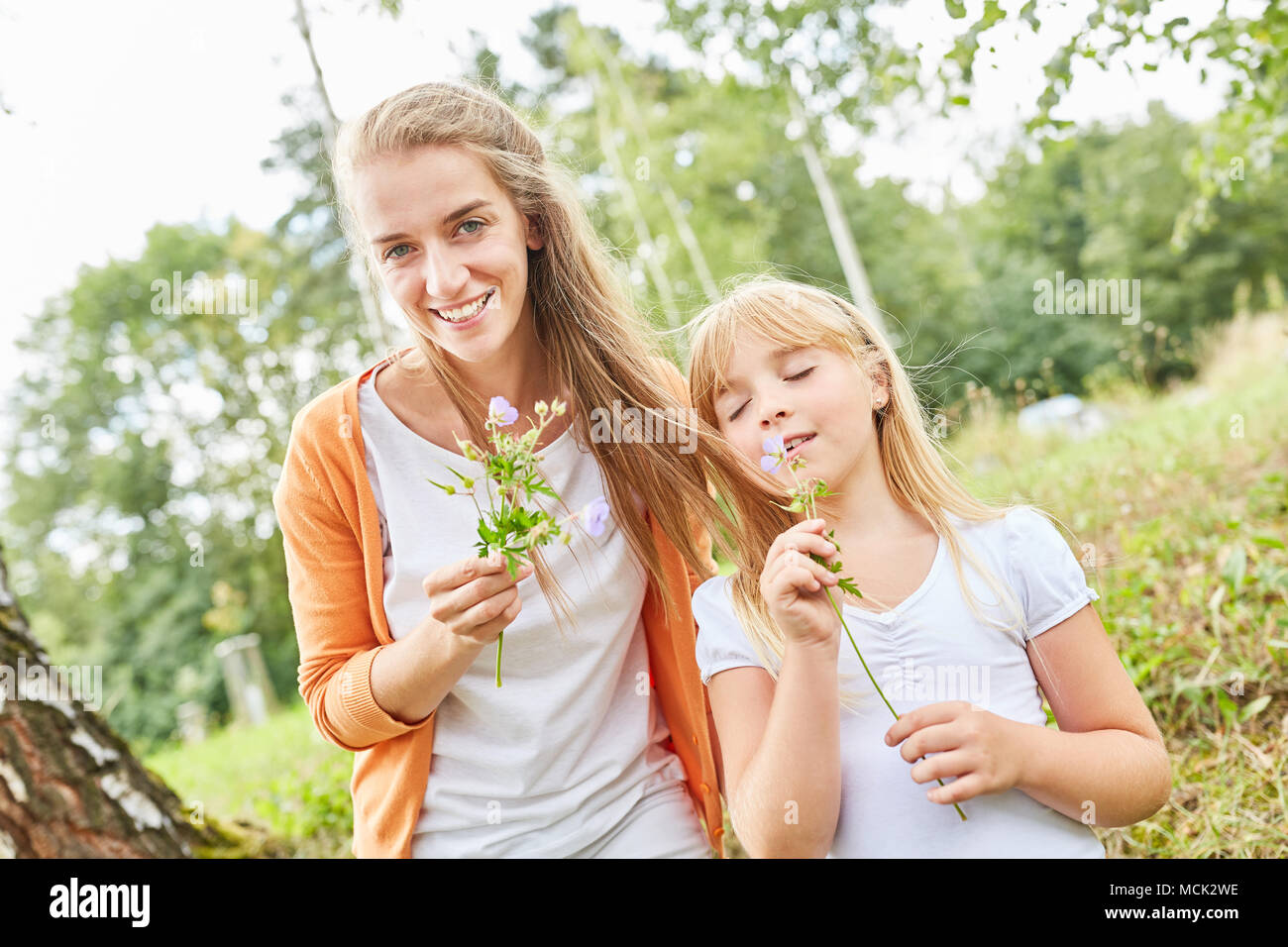 Mother and daughter together pluck flowers in the garden in summer
