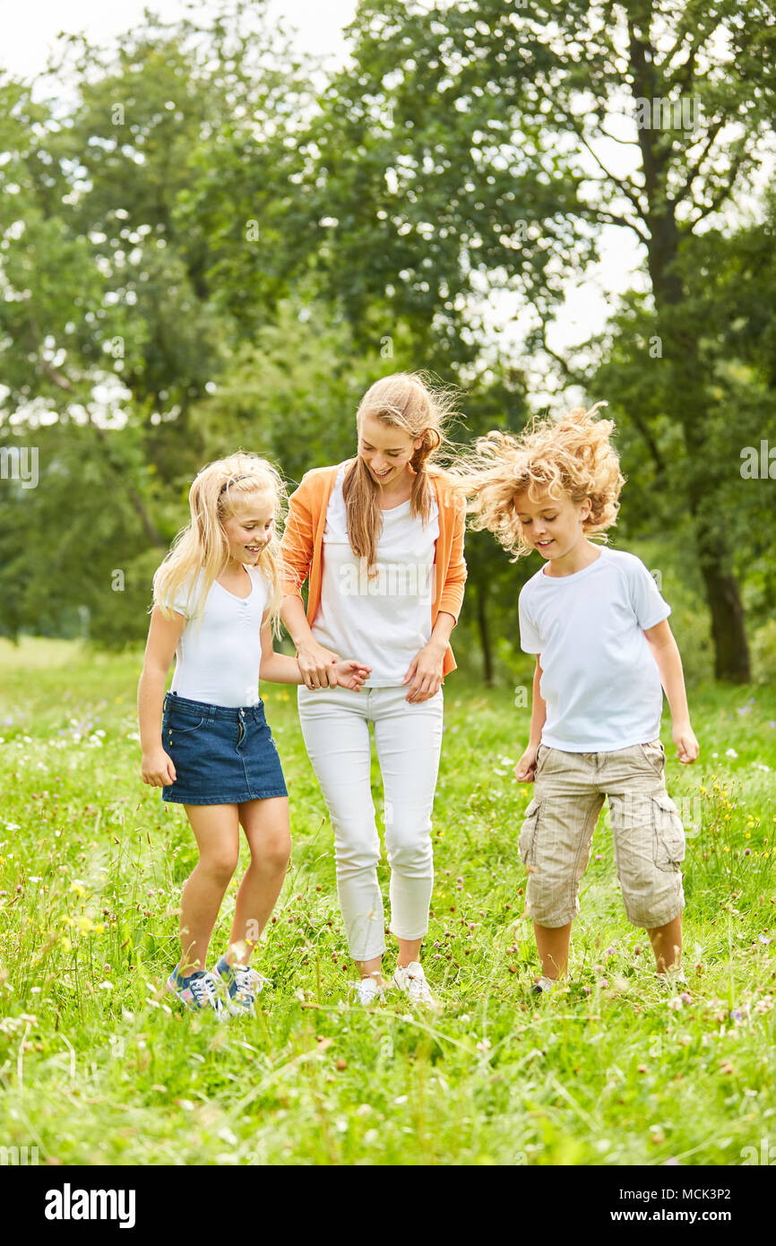 Mother and kids are dancing together on a summer meadow Stock Photo