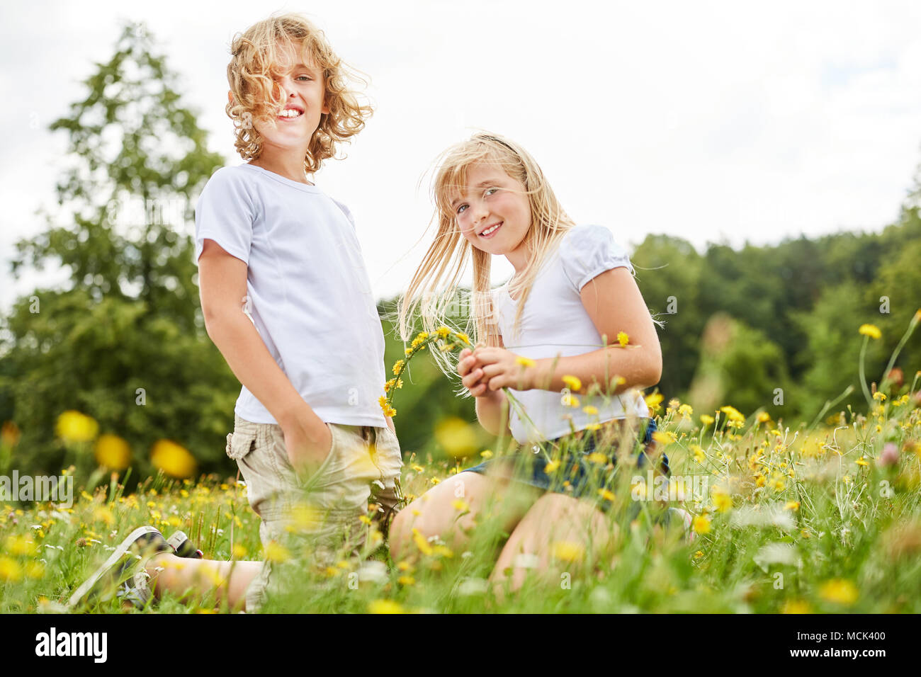 Siblings Children or friends pick flowers together in spring Stock Photo