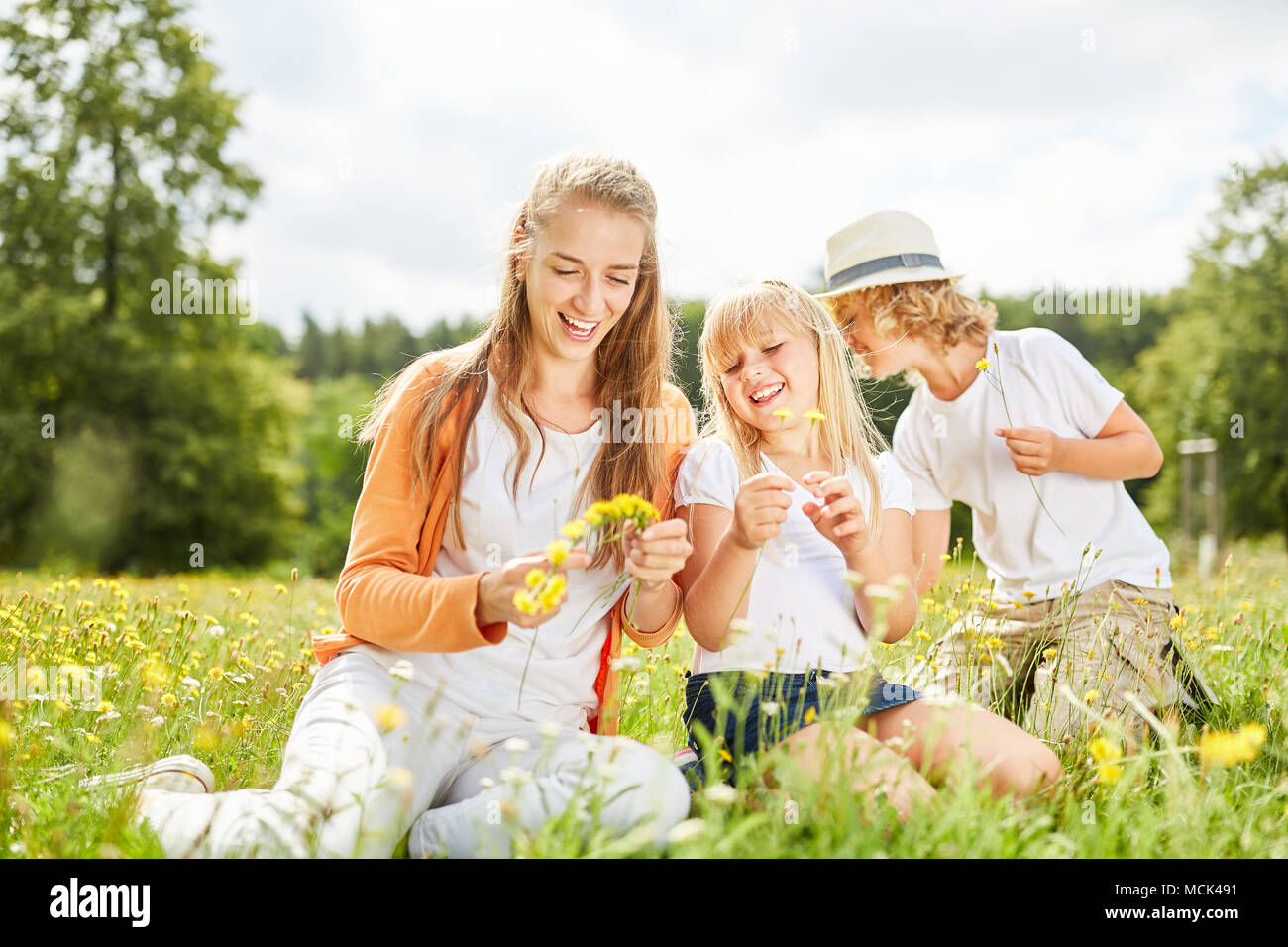 Mother and children are picking flowers together on a summer meadow Stock Photo
