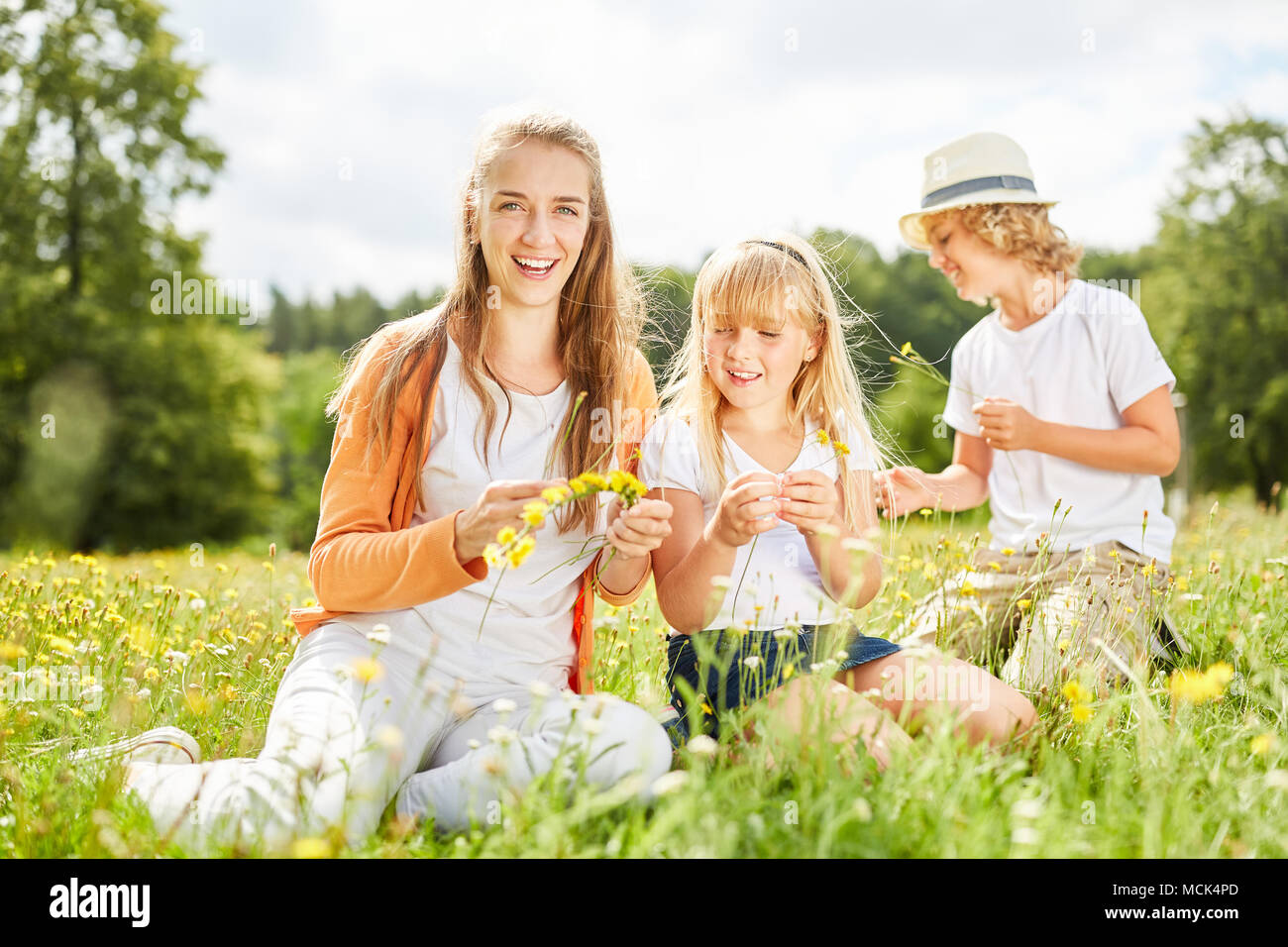 Mother and two children collect flowers together in the garden in summer Stock Photo