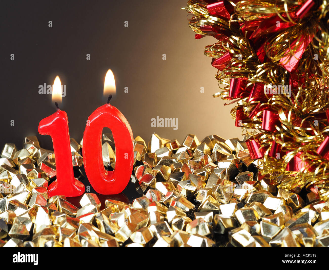 Birthday-anniversary candle showing Nr. 10  Lit red candle good for an anniversary or birthday background. Stock Photo