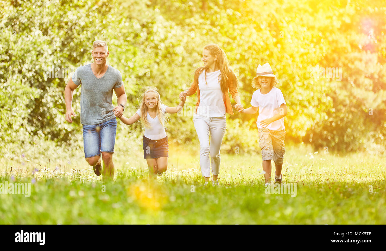 Happy family and kids run together through nature in summer Stock Photo