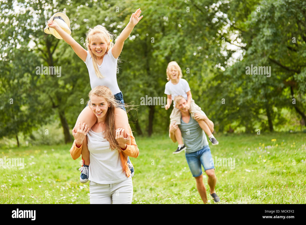 Happy girl is riding piggyback on mother's back Stock Photo