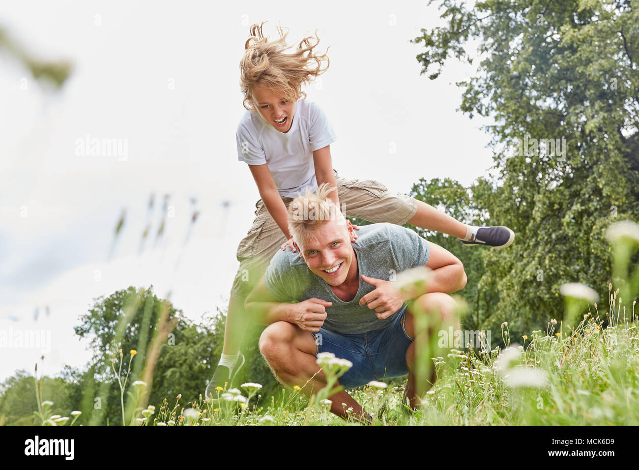 Boy in leapfrog with his father on a meadow in summer Stock Photo