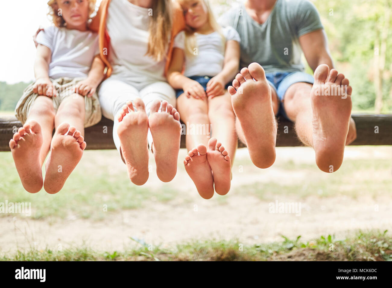 Family and children sit barefoot on a park bench and relax Stock Photo